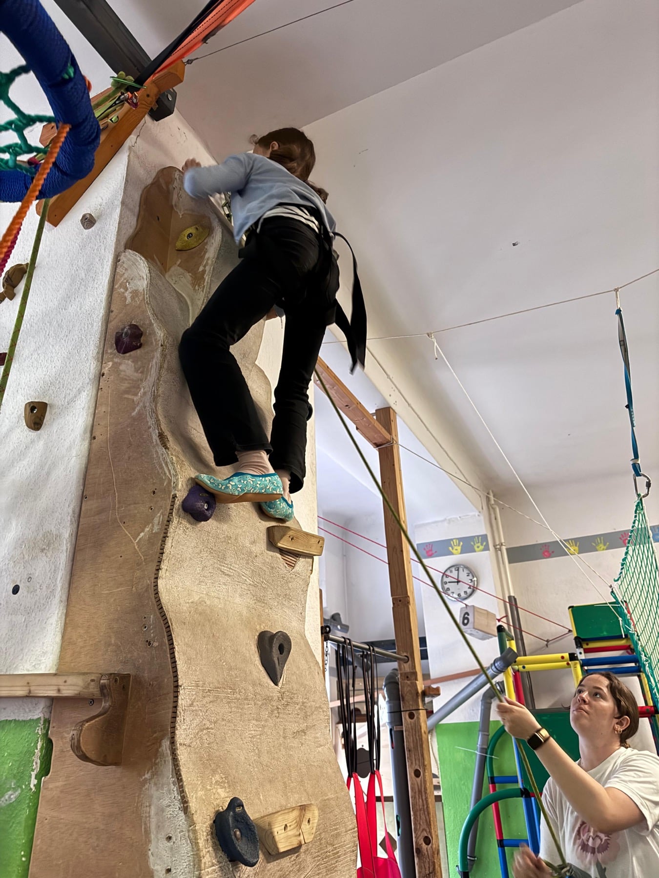 Kind klettert gesichert an der Kletterwand im jopala