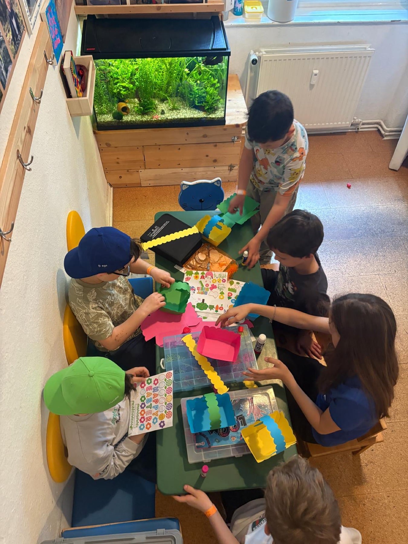 Kinder basteln gemeinsam am Tisch im jopala Feriencamp