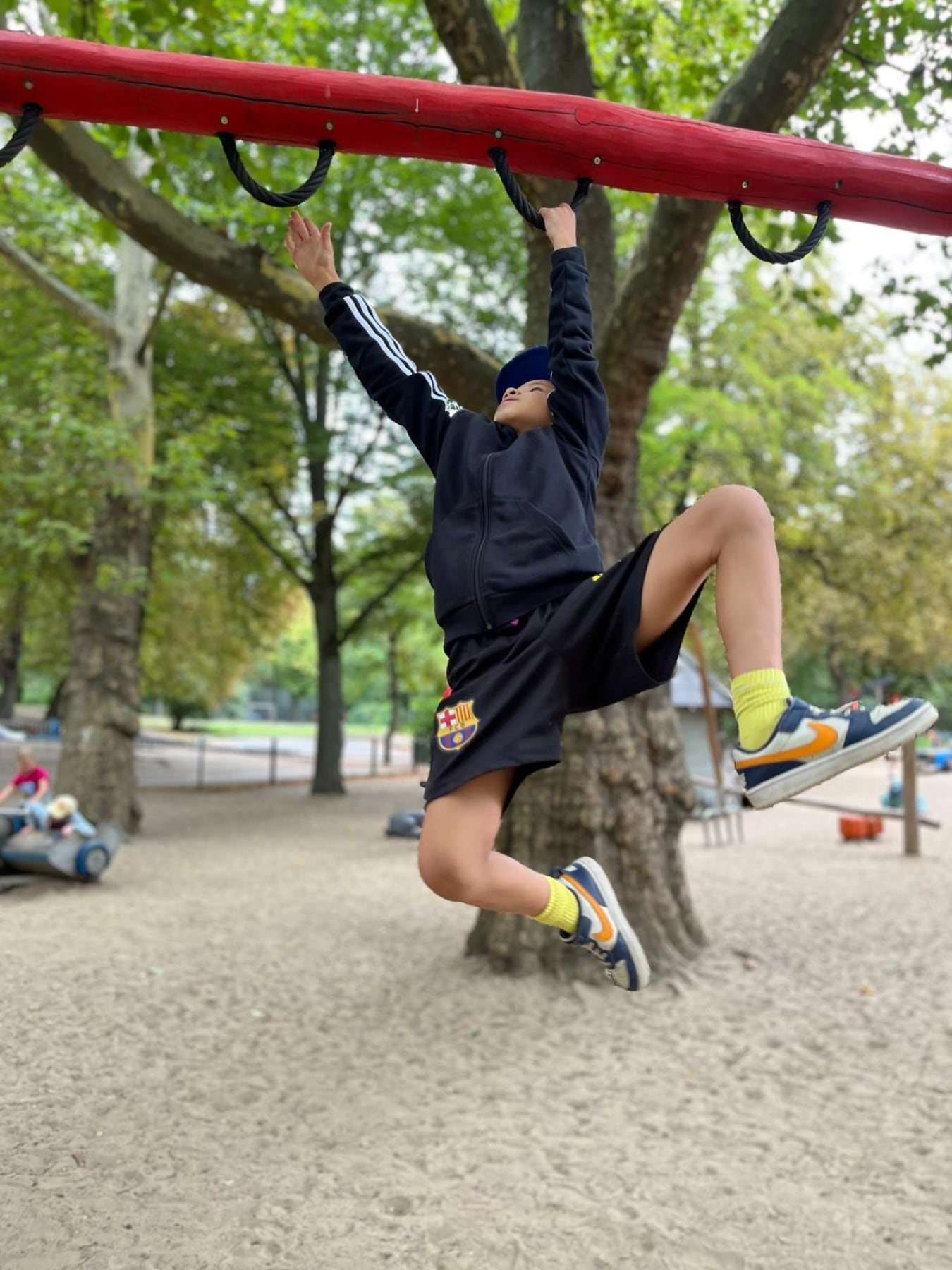 Kind hangelt im Feriencamp an einem Spielplatzgerät