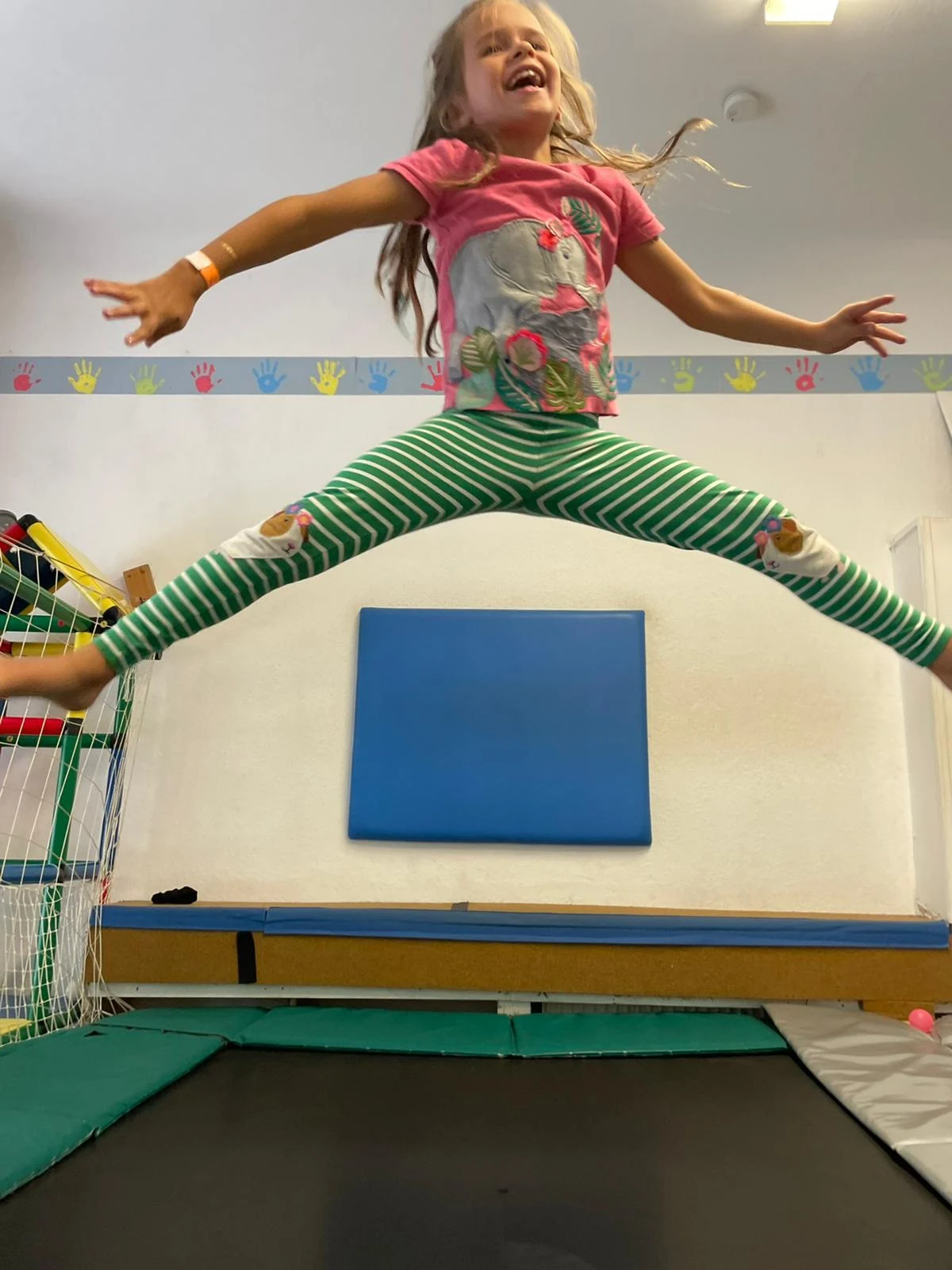 Kind mit ausgestreckten Armen und Beinen beim Trampolinspringen im jopala
